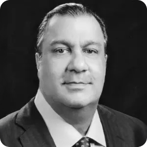 Black and white portrait of a middle-aged man wearing a suit, dress shirt, and tie, posing against a dark background.